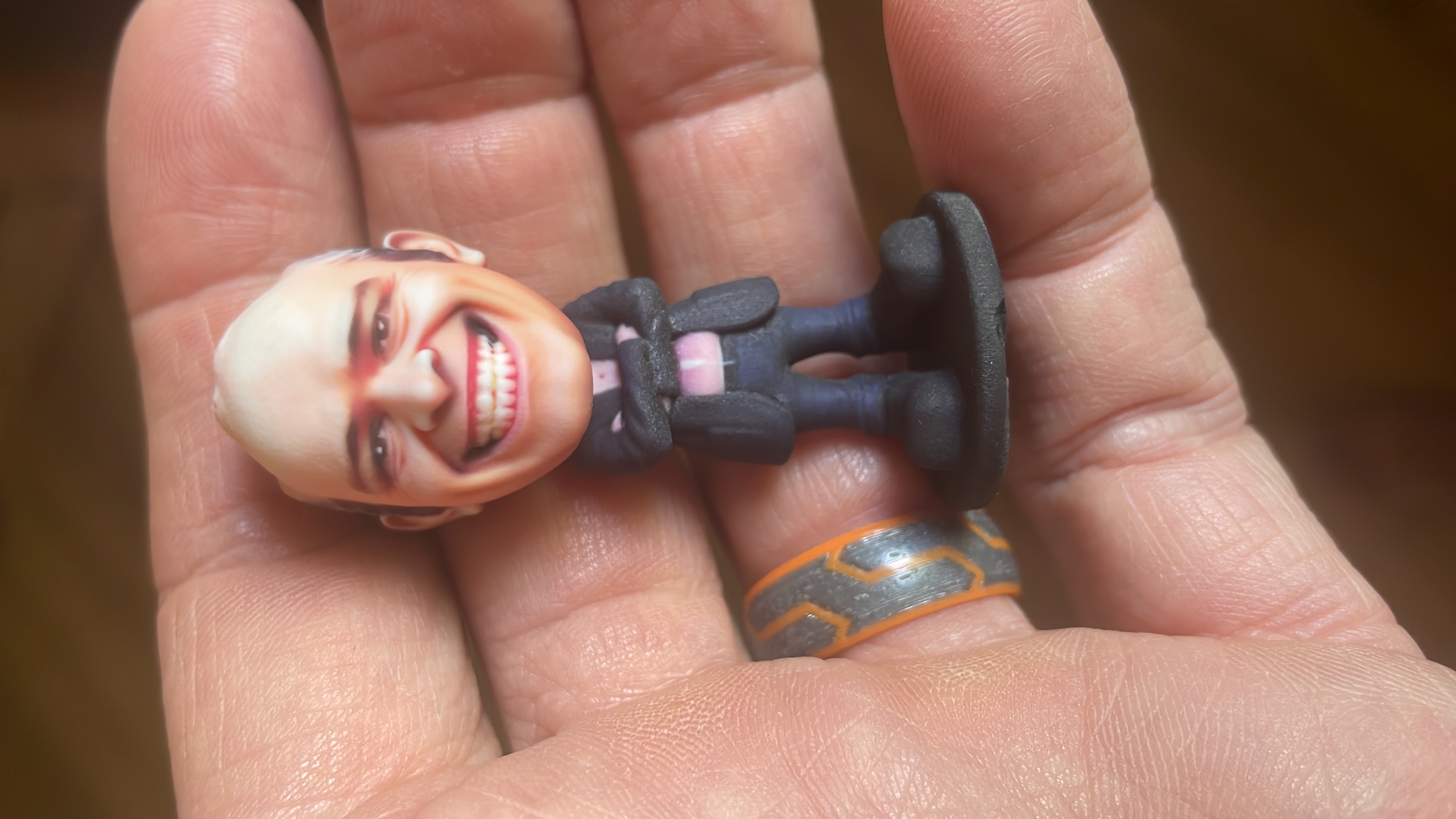 A custom bobblehead figurine held in a hand, showing its actual size